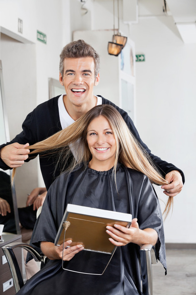 Hairstylist With Client Holding Mirror At Salon - Foto, afbeelding