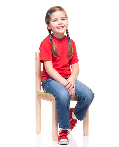 little girl wearing red t-short and posing on chair - Foto, afbeelding