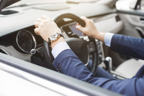 a businessman driving a prestigious car holds a mobile phone in his hand. Hasty life - Φωτογραφία, εικόνα