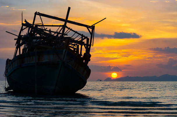 SILHOUETTE FISHERMAN BOAT WRECKED AGROUND ON LOW TIDE SEA , EVENING DUSK SKY SUNDOWN TWILIGHT IN BACKGROUND - Photo, Image