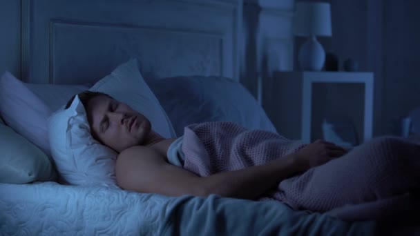 Young male sleeping unwell, suffering nightmare talking in sleep, troubles - Záběry, video