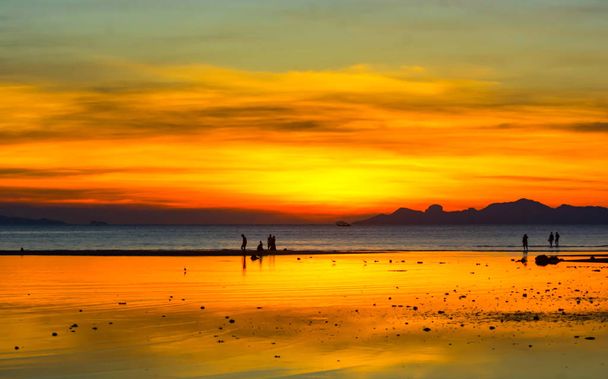 AMAZING EVENING TIME TWILIGHT SKY over OCEAN AT SEASIDE, SILHOUETTE PEOPLE TAKING A WALK ON SAND BANK, ISLAND IN BACKGROUND
 - Foto, Imagem