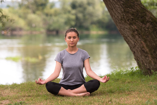mulher saudável relaxar enquanto meditar e fazer exercício de ioga na bela natureza na margem do rio
 - Foto, Imagem