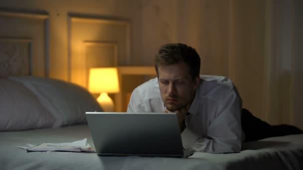 Vyčerpaná inženýr ležel na posteli, pracují na notebooku a zívat, čtení pošty - Záběry, video