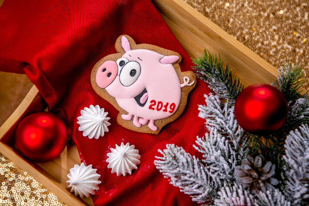 Gingerbread piggy on a stick on the breakfast table with fir branches and red ball on a background, top view. Holiday sweets. New Year and Christmas theme. Festive mood. Christmas Card. - Foto, immagini