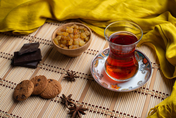 Домашнее овсяное печенье с чашкой чая на старом деревянном фоне, чашка чая с изюмом, чашка чая с шоколадом
 - Фото, изображение