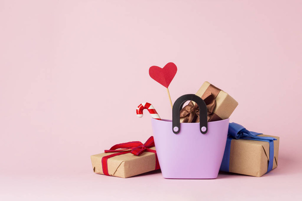 Small plastic bag for shopping, gift boxes, heart on a stick, Christmas decorations, pink background. Concept of pre-holiday shopping, gifts for friends and relatives, Christmas sale. - Photo, Image