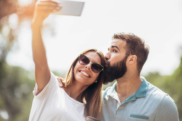 jovem casal usando telefone celular tirar uma selfie no parque
 - Foto, Imagem