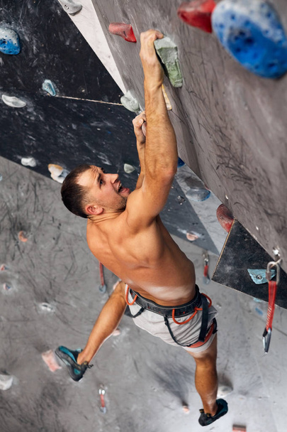 Male professional climber at indoor workout at bouldering centre. - Foto, Imagen