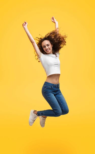 Casual slim woman in jump on yellow background - Fotoğraf, Görsel