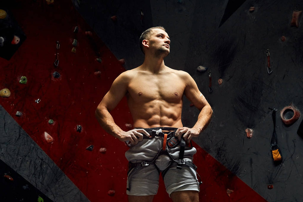 Portrait of cheerful rock climber in indoor climbing gym - Foto, Imagen
