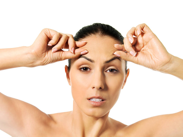 Worried young woman checking wrinkles on forehead - Photo, Image