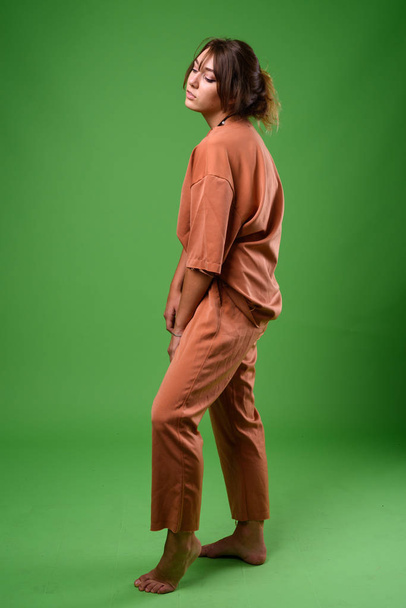 Στούντιο πλάνο της νεαρής όμορφης γυναίκας σε πράσινο φόντο - Φωτογραφία, εικόνα