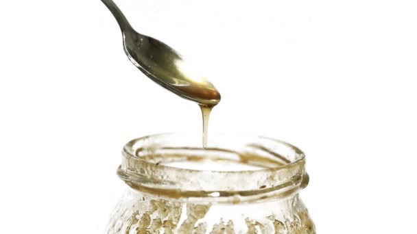 Closeup view of silver spoon with honey, white background - Footage, Video