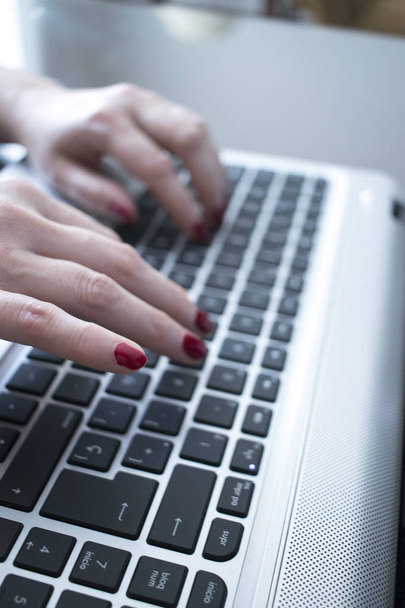 Секретарша печатает на ноутбуке клавиатуры компьютера клавиши с руками с красным лаком для ногтей
. - Фото, изображение
