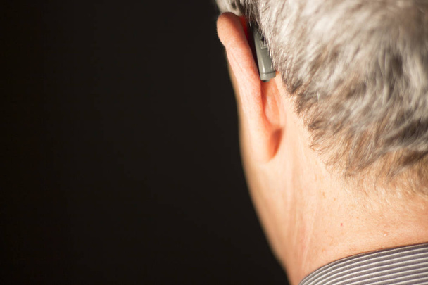 聴覚障害者高齢者男の耳で身に着けている現代デジタル高技術補聴器. - 写真・画像