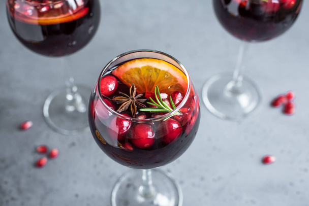 Red Sangria with oranges, pomegranate seeds, cranberry, rosemary and spices - homemade festive drink mulled wine for Christmas time. - Foto, Imagem