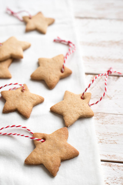 Christmas star shaped gingerbread cookies with red ropes for Christmas tree decoration on white background close up. - Fotó, kép