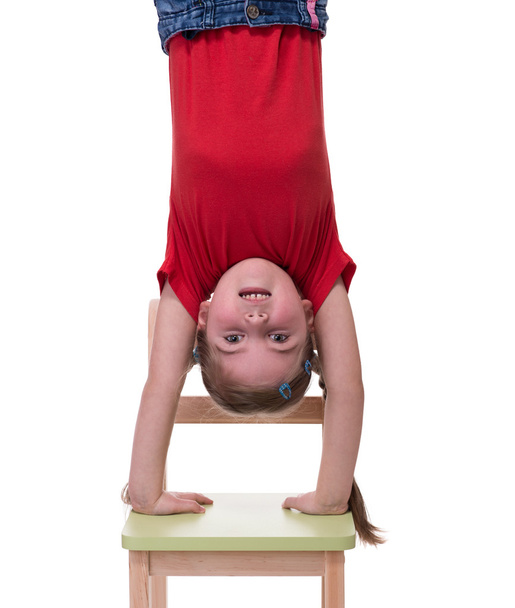 little girl standing on her hands on chair - Fotó, kép