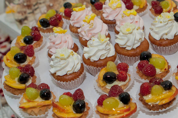 cupcakes with raspberries, grapes and peach on a wedding table. - Fotografie, Obrázek