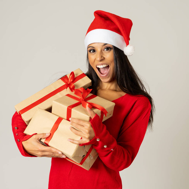 Smiling girl in santa christmas hat with pile gift boxes looking excited and happy isolated copy space on background in Christmas holidays shopping sales celebration holidays and Merry Christmas. - Foto, Imagem