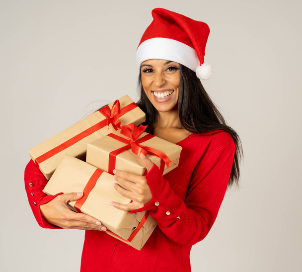 Smiling girl in santa christmas hat with pile gift boxes looking excited and happy isolated copy space on background in Christmas holidays shopping sales celebration holidays and Merry Christmas. - Fotografie, Obrázek