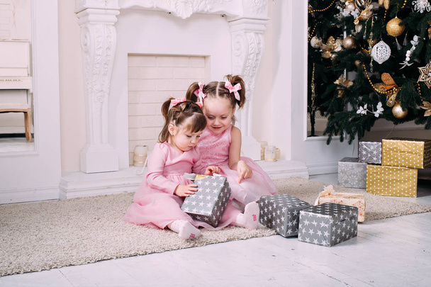 Girls with Christmas presents. Two kids having fun with christmas tree.  - Photo, image