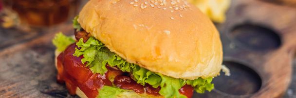 Close-up of fresh burger with french fries on wooden table. - Foto, afbeelding
