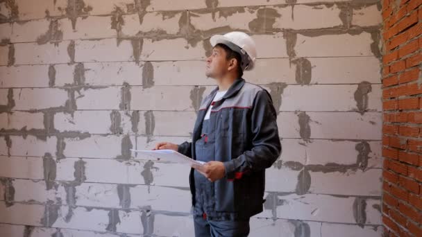 Człowiek z dokumentami zwiedzania pokój w budynku w trakcie budowy - Materiał filmowy, wideo