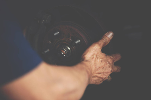 Car mechanic or serviceman checking a disc brake and asbestos brake pads it's a part of car use for stop the car for safety at front wheel this a new spare part for repair at car garage - Photo, Image