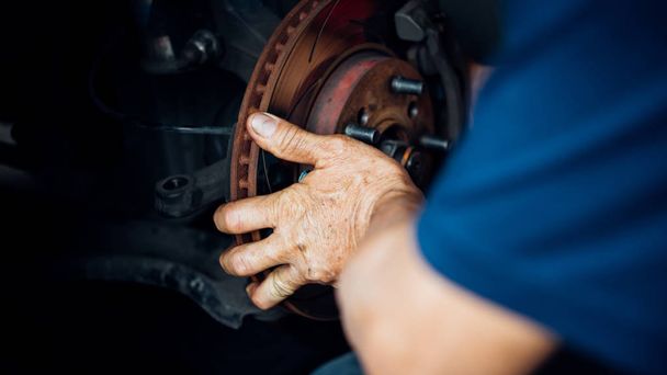 Car mechanic or serviceman checking a disc brake and asbestos brake pads it's a part of car use for stop the car for safety at front wheel this a new spare part for repair at car garage - Photo, Image