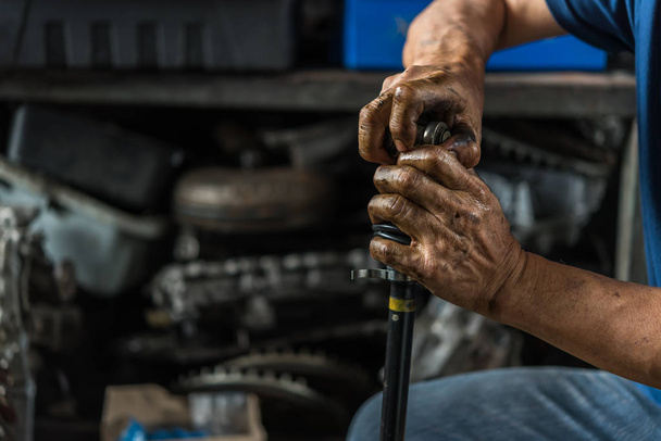 Car mechanic or serviceman disassembly and checking a car alloy chrome wheel for fix and repair suspension problem at car garage or repair shop - Fotó, kép