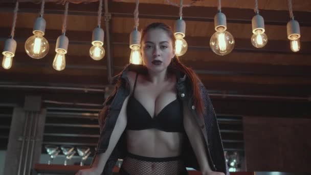 Sexy brunette woman in black lingerie and jacket posing on the bar table in luxurious modern interior - video in slow motion - Footage, Video