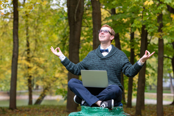 Un hombre en un pedestal que finge ser una estatua medita en la posición de loto en el parque
. - Foto, imagen