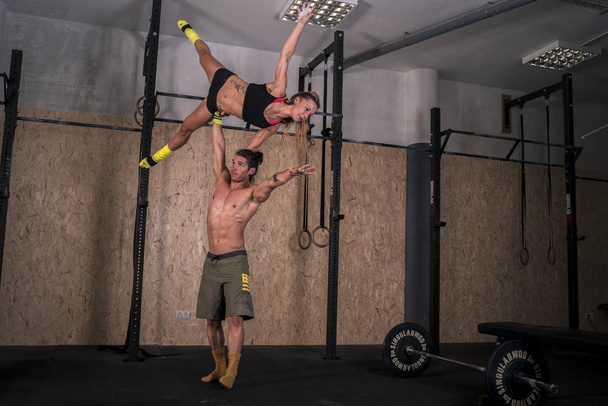 Αρσενικά και θηλυκά ακροβάτες εκτελούν γυμναστικές Γιόγκα ασκήσεις στο γυμναστήριο - Φωτογραφία, εικόνα