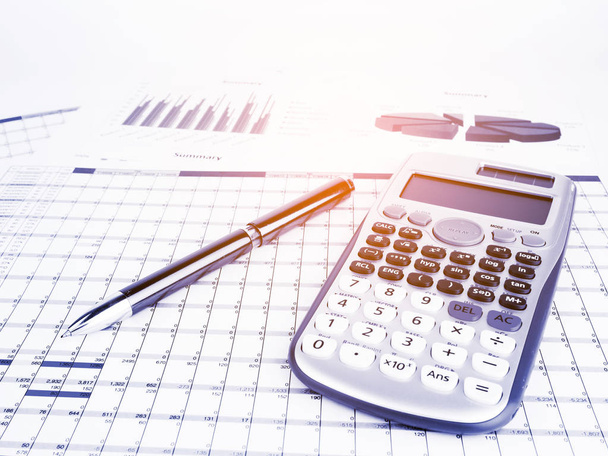 Calcolatrice e penna con grafici aziendali e riportare informazioni di base per i concetti finanziari ed economici, tono blu
. - Foto, immagini