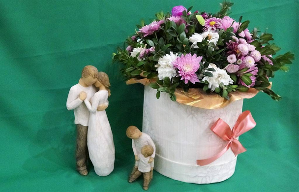 Touching Wooden figures of parents and children near a bouquet of flowers. The image in pastel tones. - Photo, Image