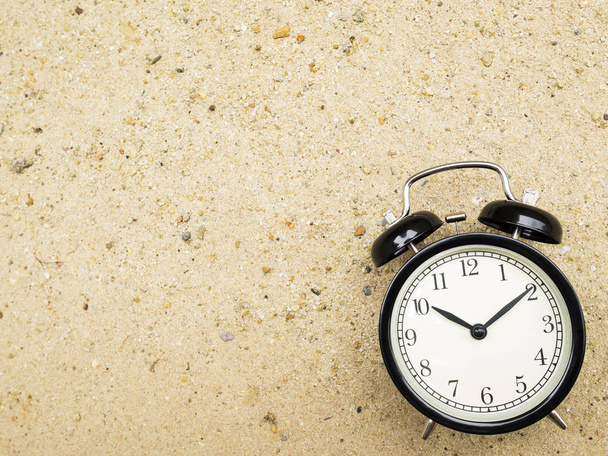 Reloj despertador en arena de playa, mostrando las diez en punto
. - Foto, Imagen