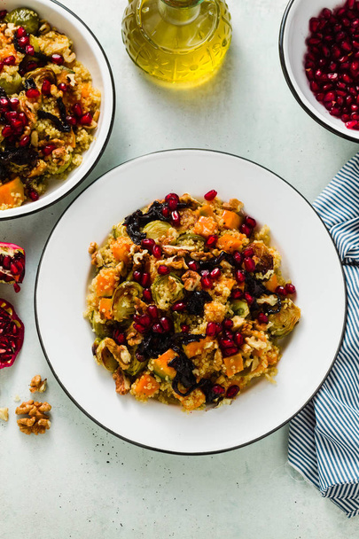 Delicious autumn festive salad of pumpkin, brussels sprouts, quinoa, walnuts, caramelized onions and pomegranate seeds. Healthy Vegan Gourmet Recipe - Foto, afbeelding