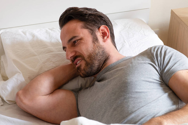 Homem sentindo o pescoço duro depois de dormir na cama
 - Foto, Imagem