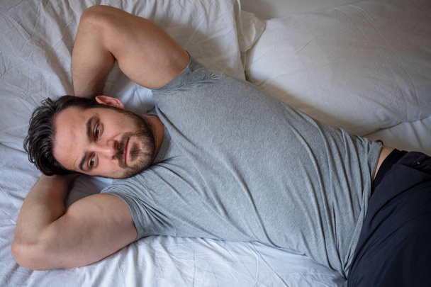 Uitgerust fit man liggend in het bed comfortabel gevoel - Foto, afbeelding