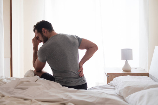 Homem acordando de manhã e sofrendo por dor nas costas
 - Foto, Imagem