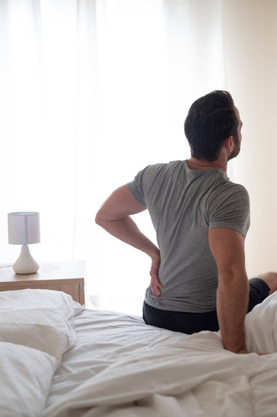 Mann spürt Rückenschmerzen nach dem Schlafen im Bett - Foto, Bild