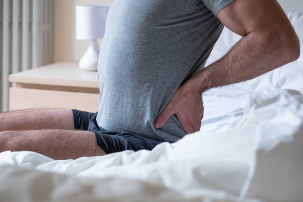 Hombre sintiendo dolor de espalda después de dormir en la cama
 - Foto, Imagen