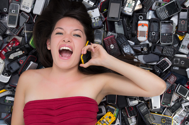 Woman on top of a Pile of mobile cell phones - Foto, afbeelding
