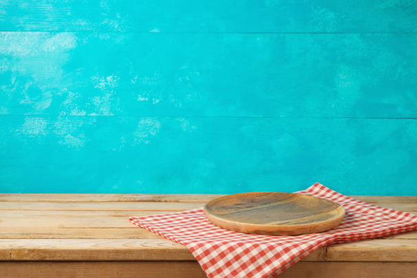 Piatto o vassoio in legno vuoto sul tavolo da cucina con tovaglia su sfondo blu
 - Foto, immagini