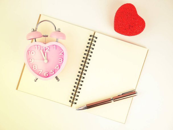 Вид сверху ноутбука будильник и ручка с красным сердцем, винтажный фильтр
. - Фото, изображение