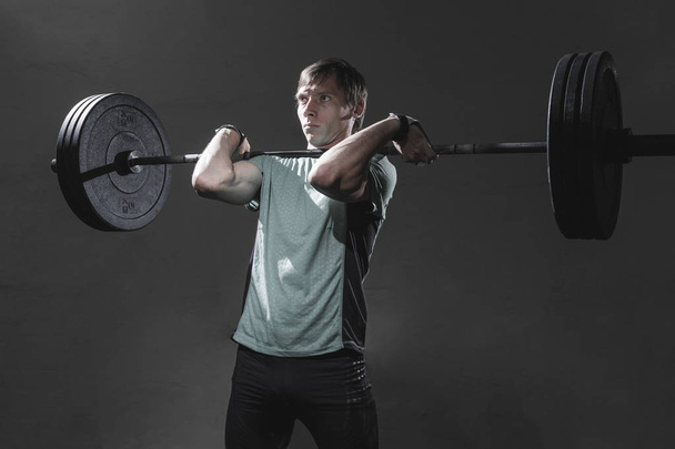 Serious sportsman lifting barbell - Photo, image