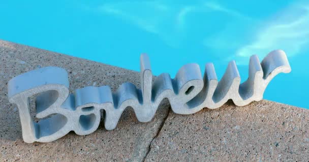 Fából készült "Bonheur" szómegjelölés francia, ami azt jelenti a boldogságot. Kék víz medence háttér - Dci 4k felbontás - Felvétel, videó