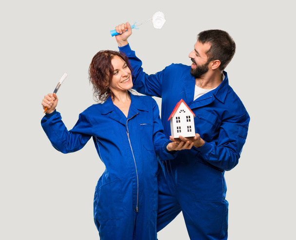 Painters holding a little house on isolated grey background - Photo, Image